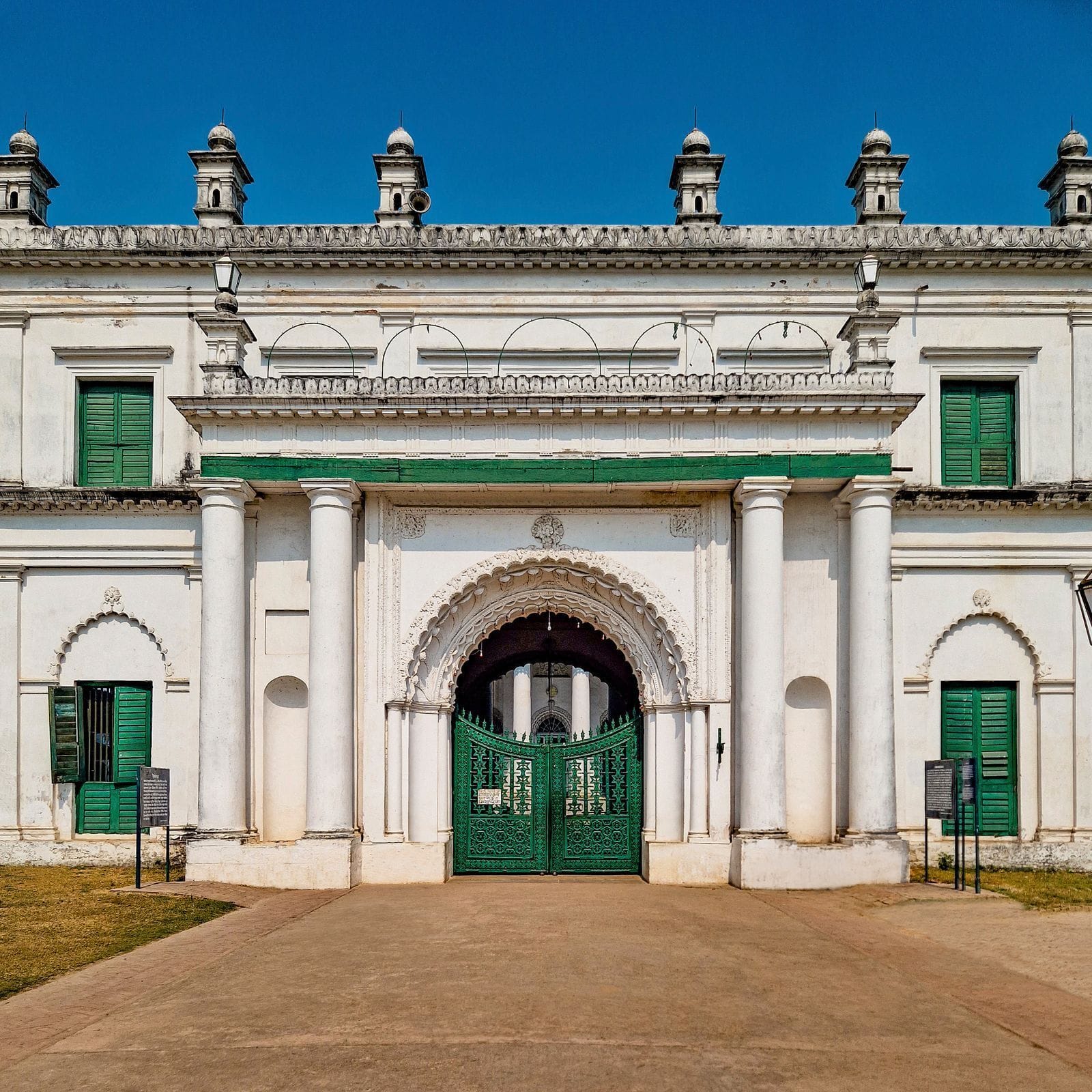 A white and green historic facade with an arched entrance