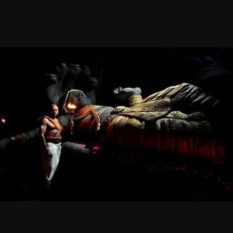 A reclining deity displayed within a dark shrine