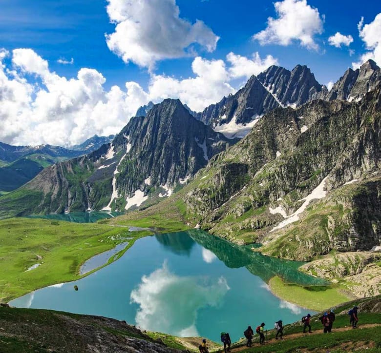 A small mountain lake reflecting jagged peaks and clouds