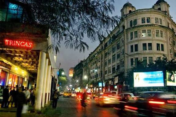Traffic passing restaurants and shops on a Kolkata street