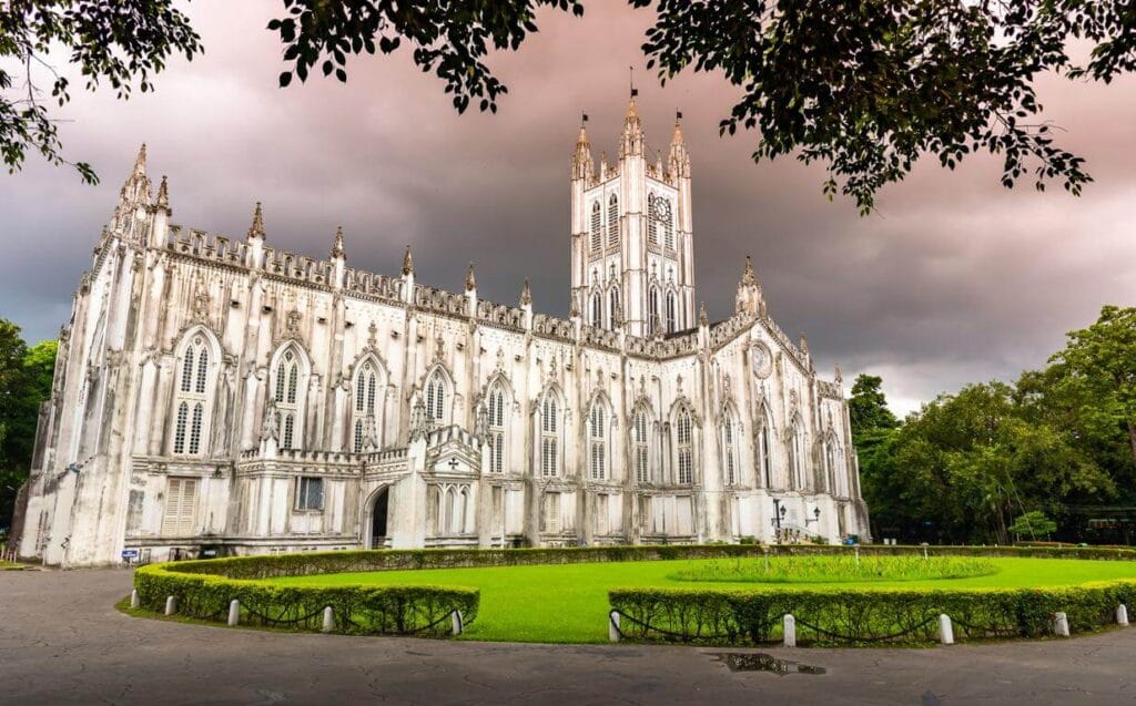 A white Gothic cathedral beside trees and a lawn