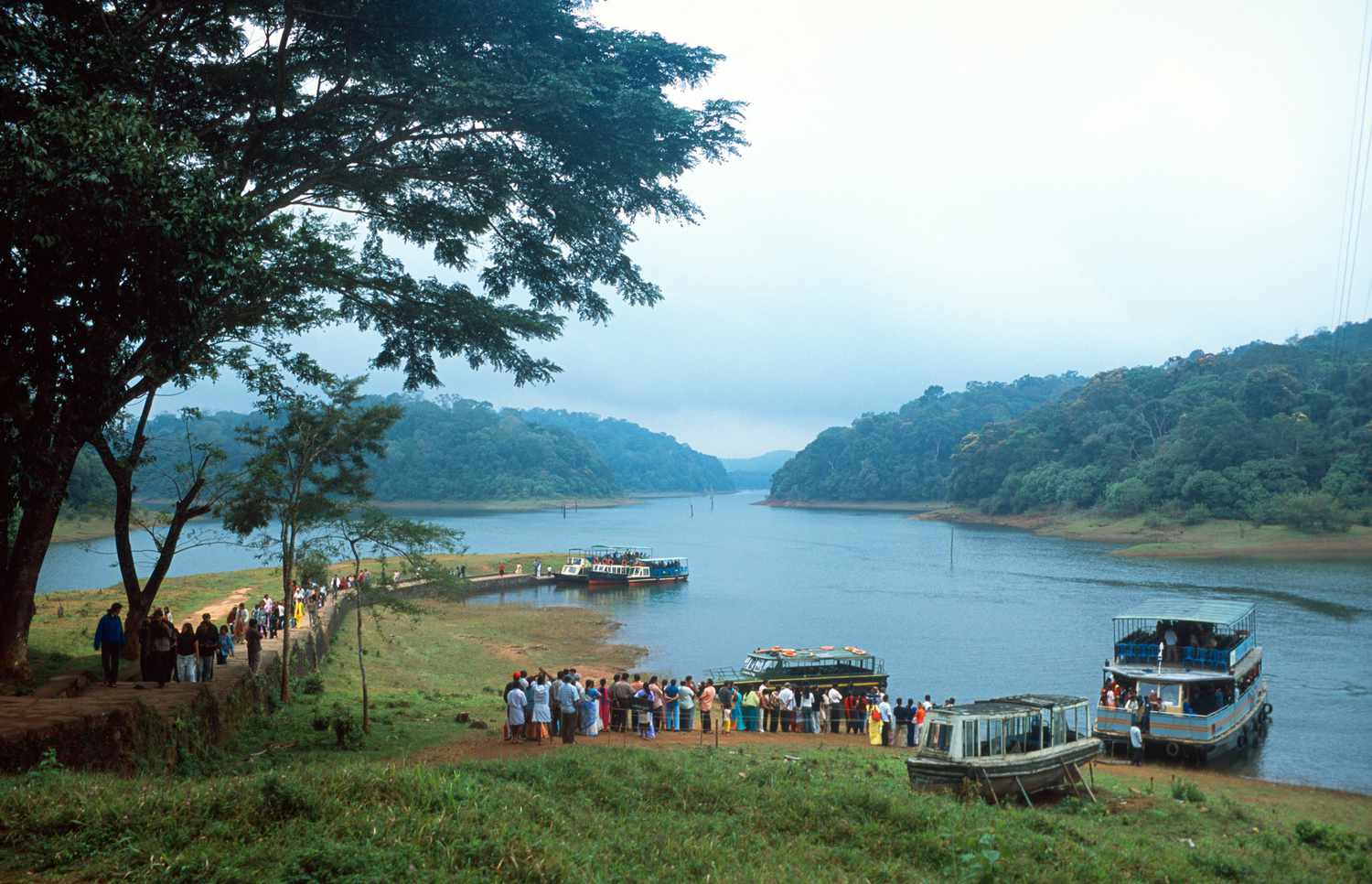 Boats moored on a lake surrounded by forested hills