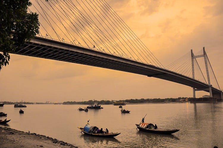 Boats beneath a cable-stayed bridge at sunset