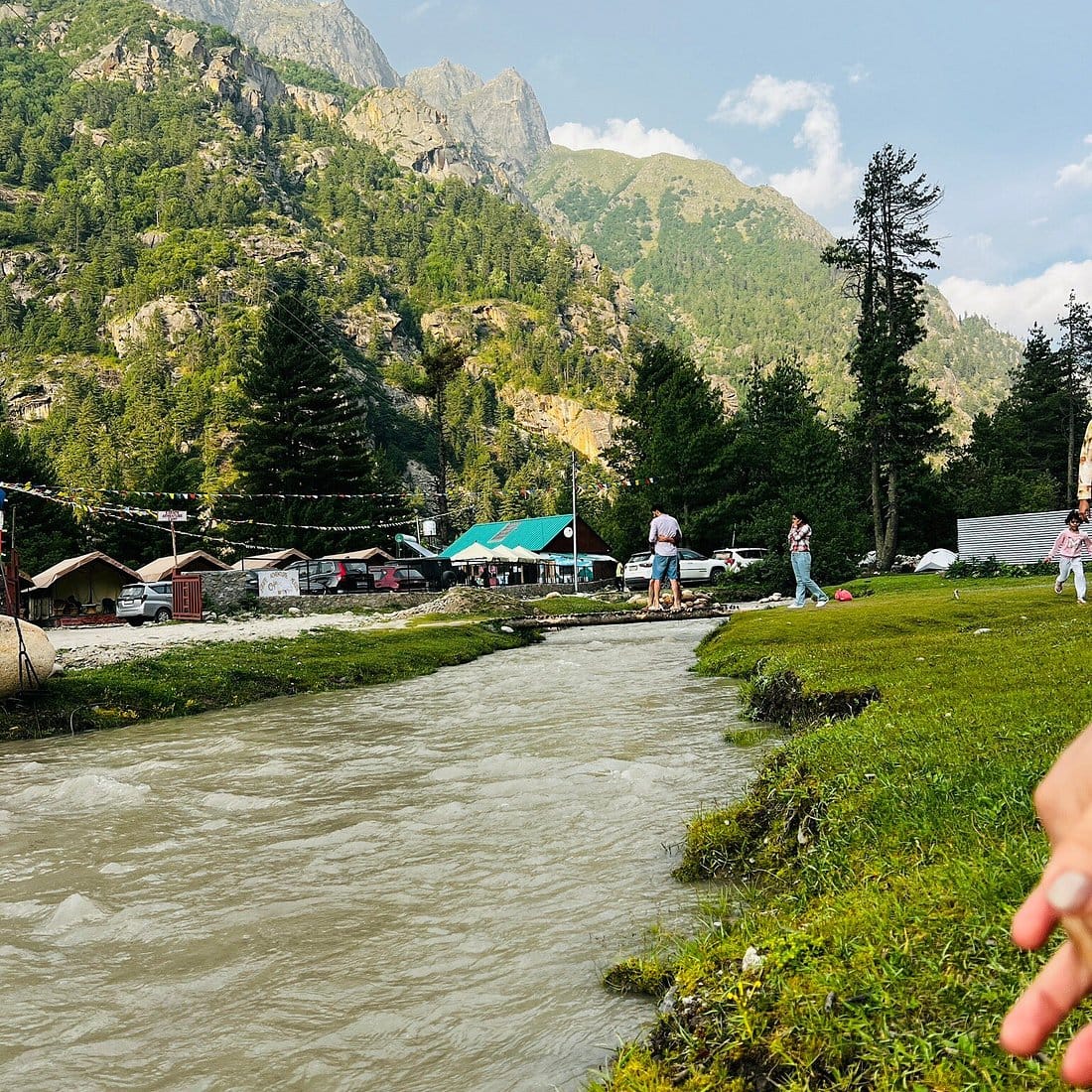 A mountain river flowing past trees and small buildings