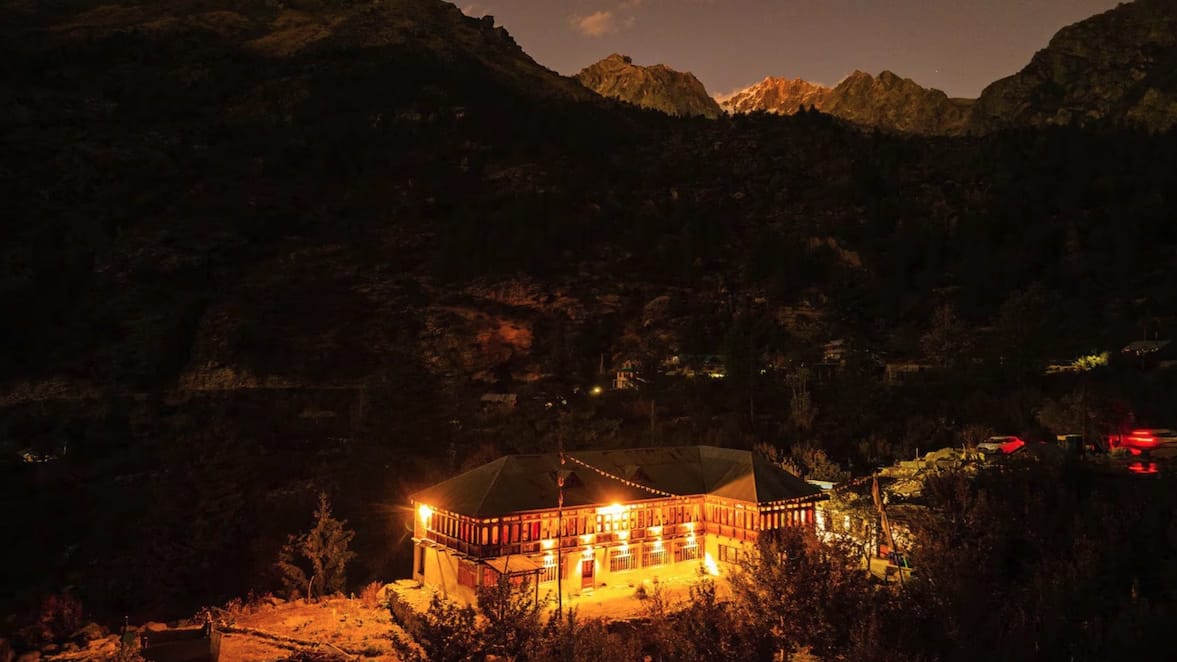 An illuminated monastery against dark mountain slopes