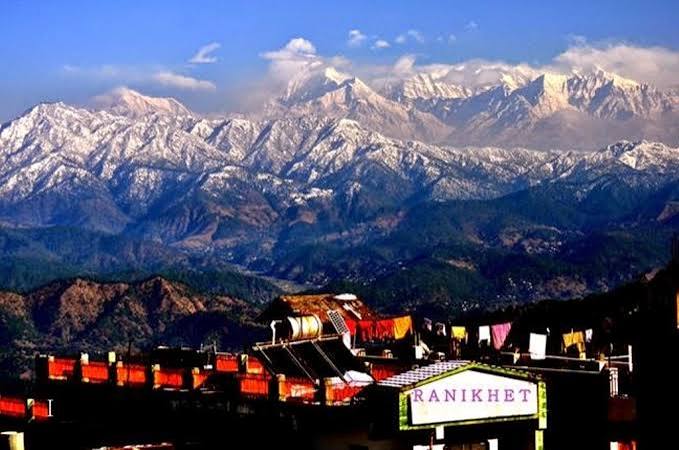 A village beneath a wide range of snow-covered Himalayan peaks