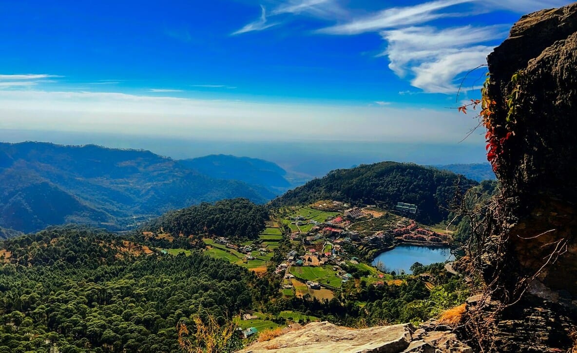 A hillside town and lake among green mountain ridges