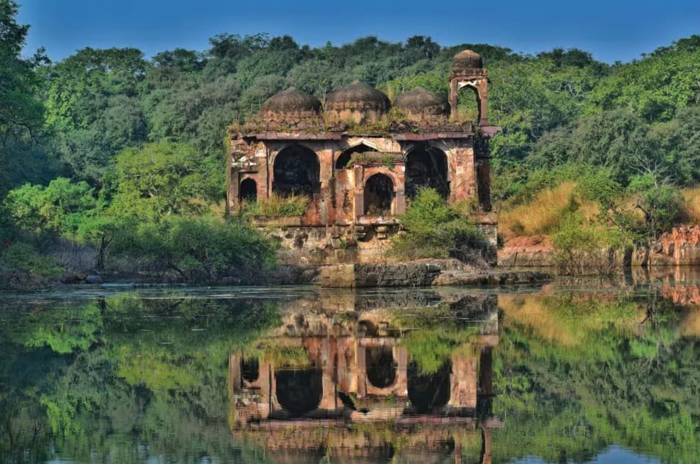 A historic pavilion reflected in a wooded lake