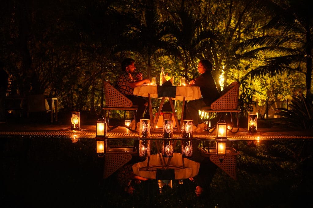 A candlelit table beneath trees at night