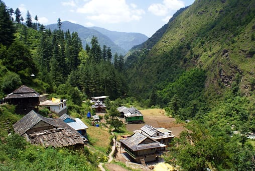 Traditional village buildings across a green mountain valley