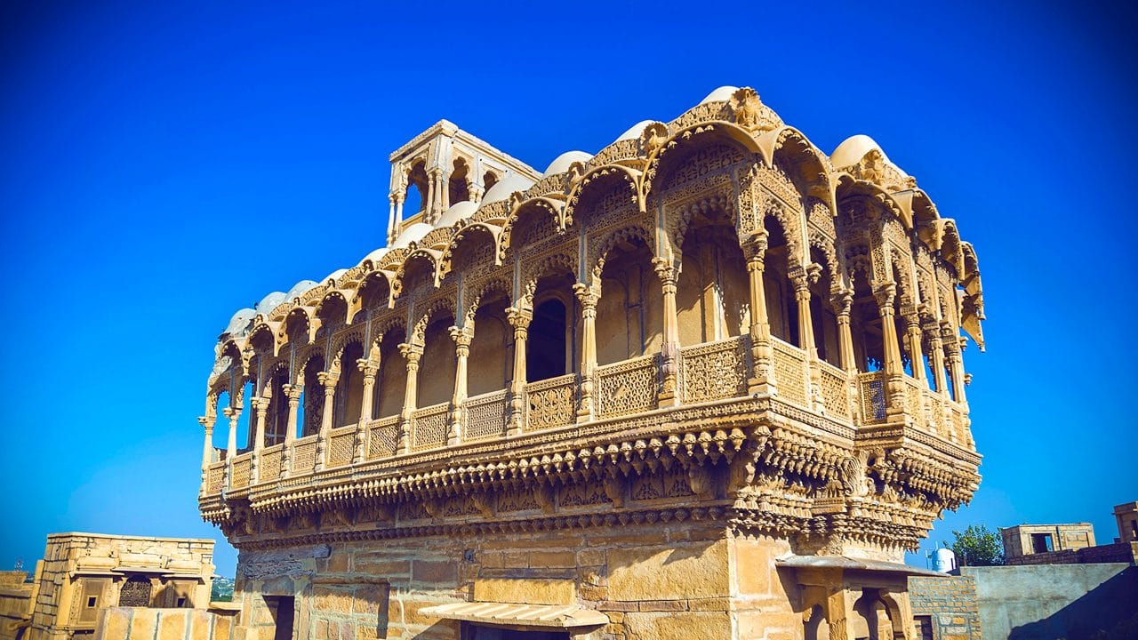 A carved sandstone balcony beneath a blue sky