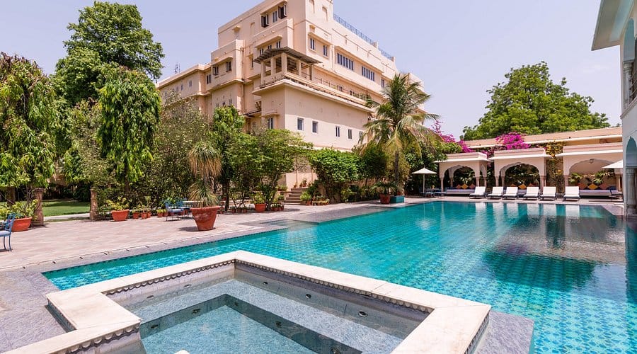 A swimming pool beside a pink heritage hotel