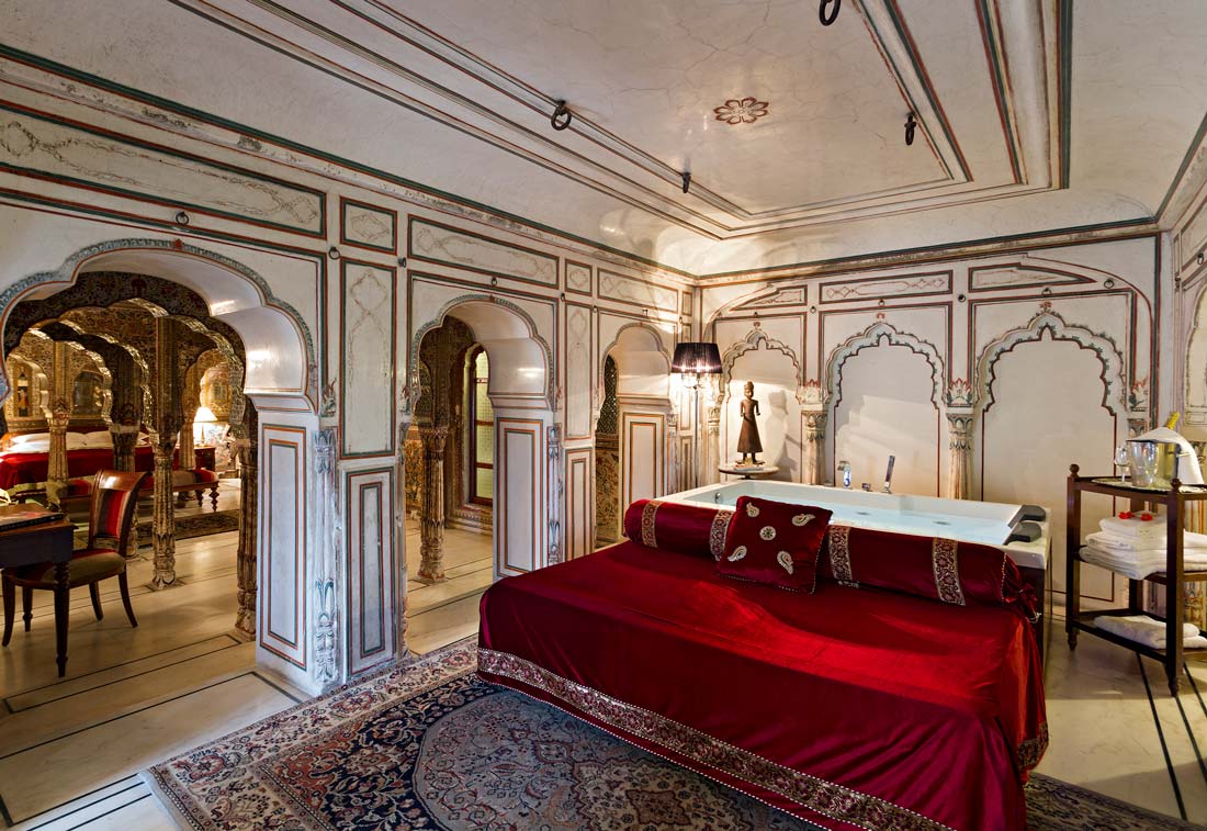 A red bed within an ornate heritage hotel bedroom
