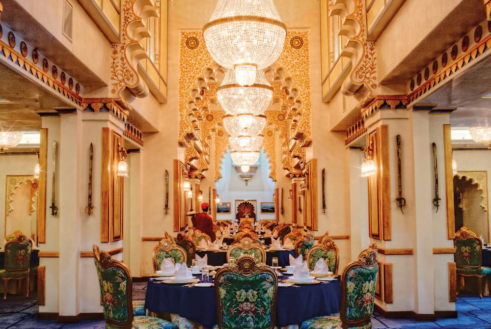 A chandelier-lit dining room with carved columns