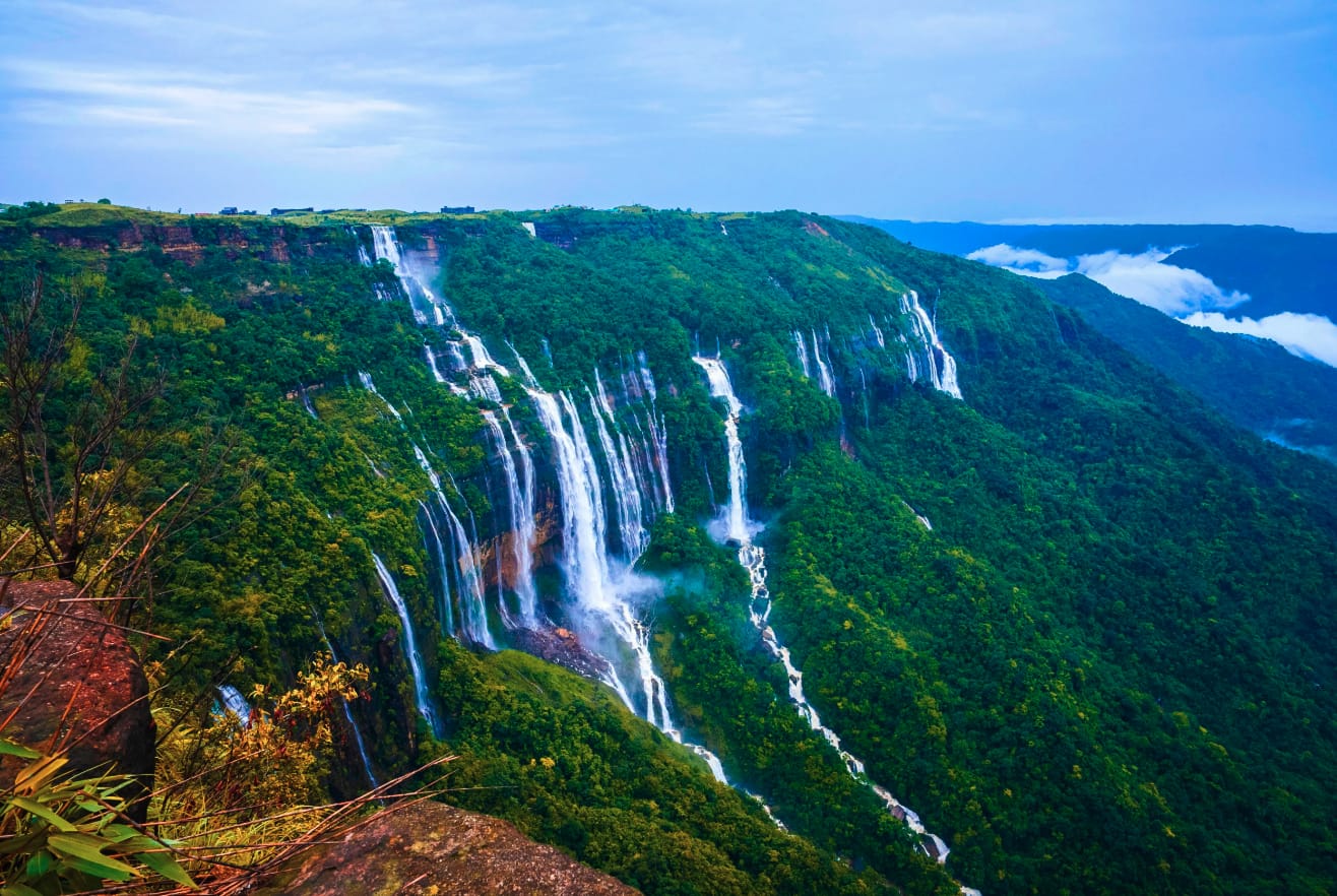 Multiple waterfalls descending a steep green plateau