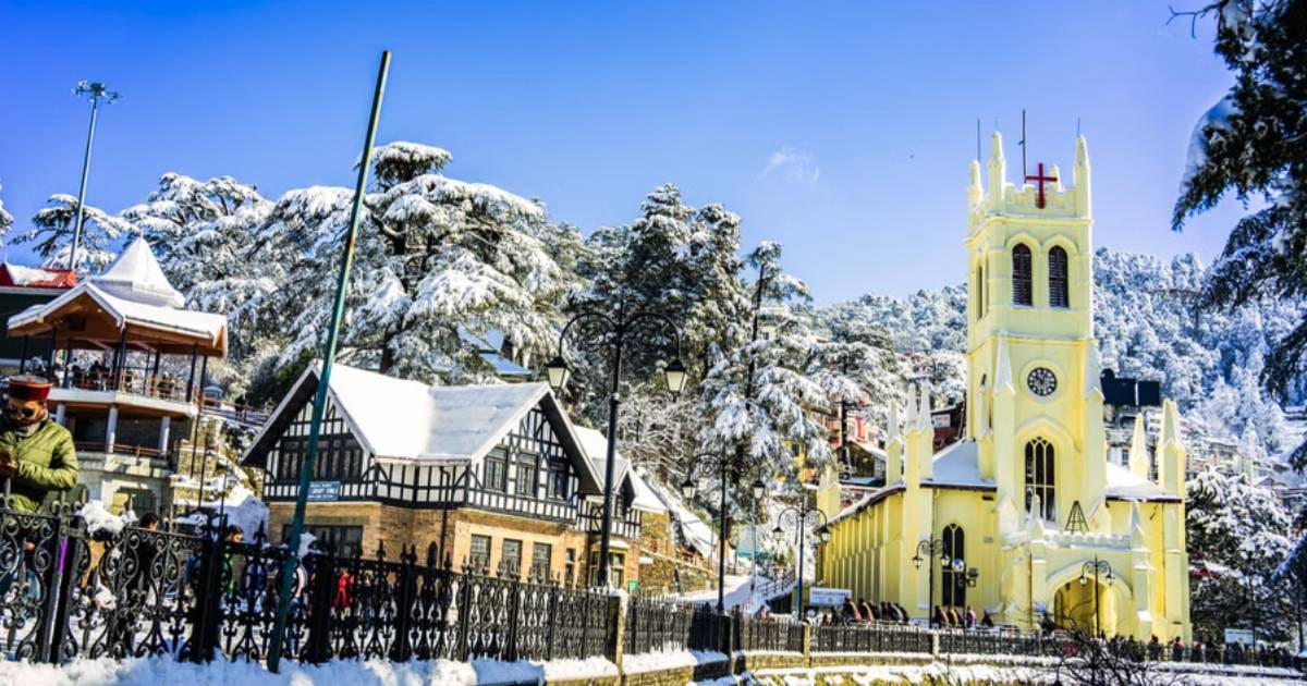 A yellow church beside snow-covered town buildings