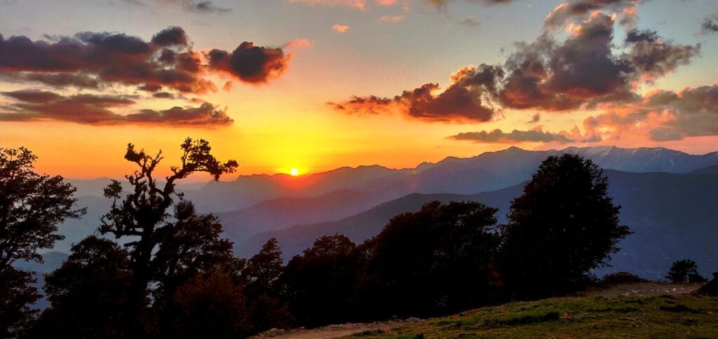 The sun setting behind layered mountain ridges
