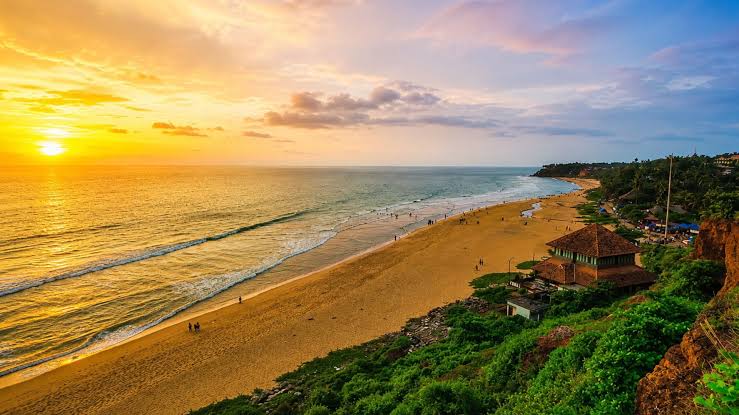 Sunset over a broad beach below a coastal cliff