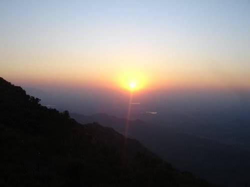 The sun setting over distant mountain ridges