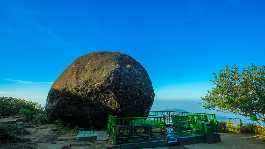 A large rounded rock above a fenced viewpoint