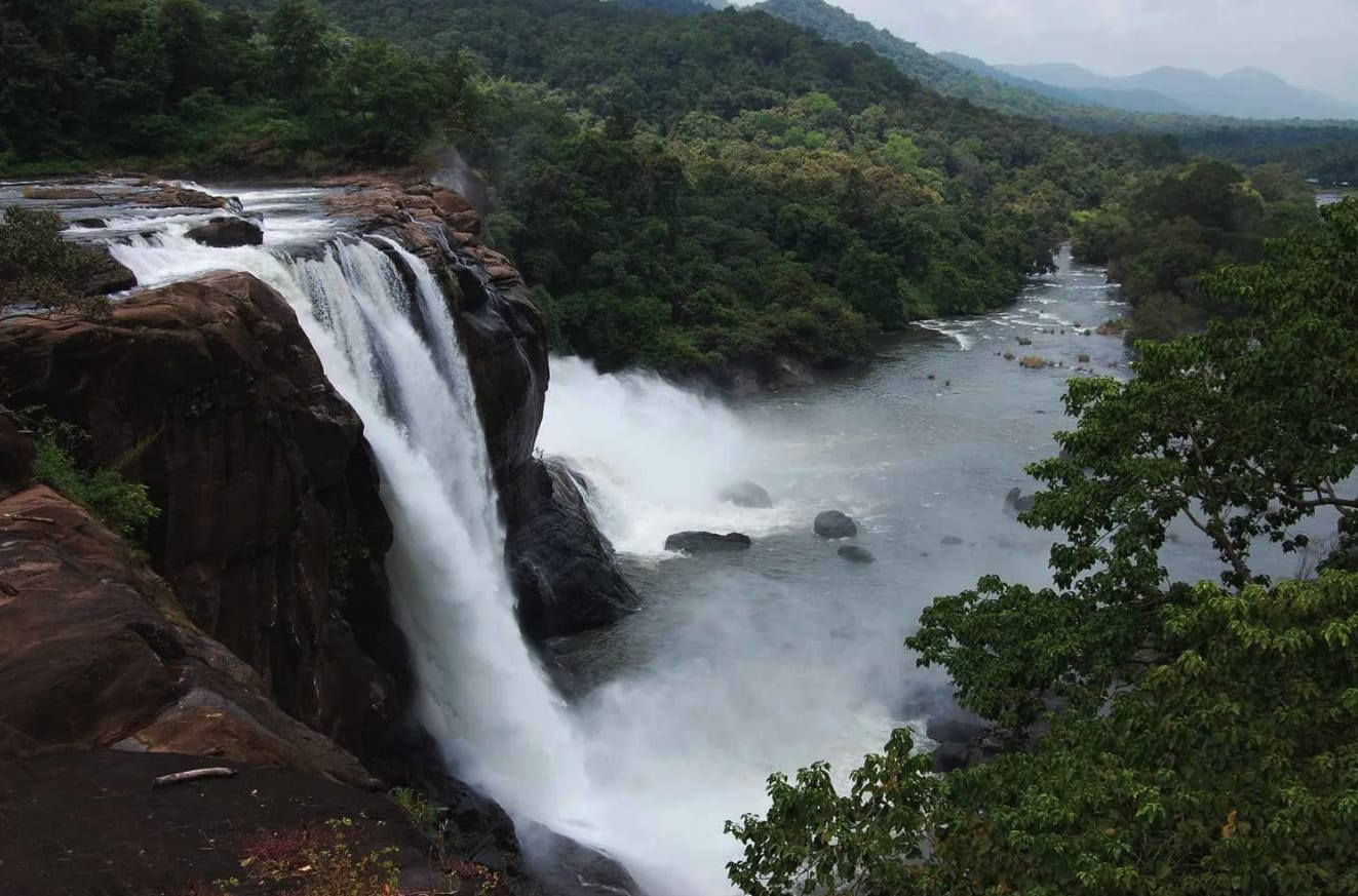 A broad waterfall plunging into a wooded gorge