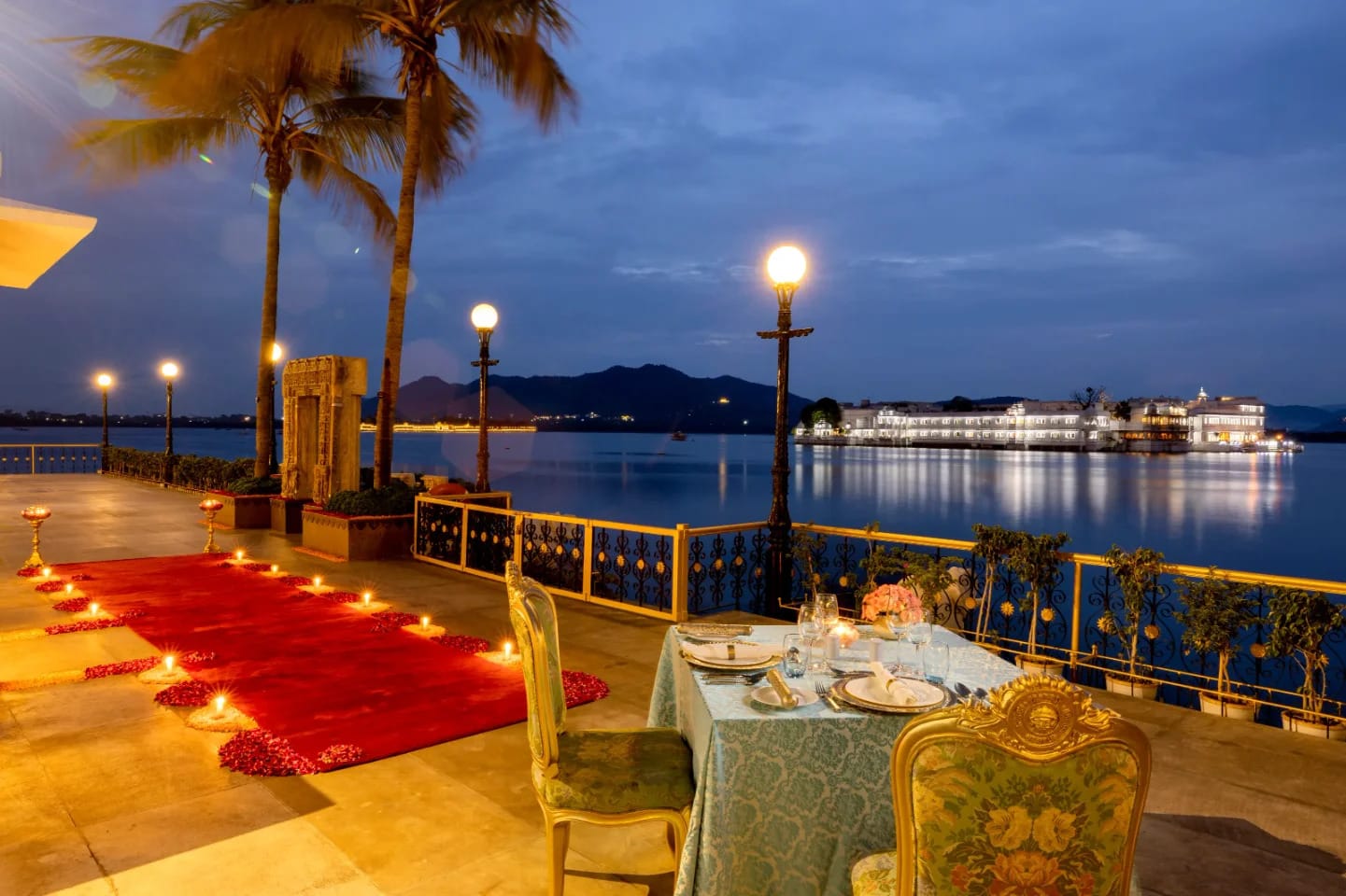 A dining table on a lakeside terrace illuminated at dusk