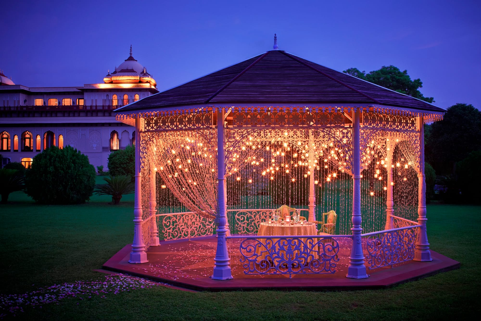 A garden gazebo glowing with strings of lights after sunset